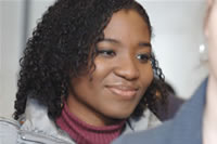 A smiling young woman in conversation, wearing a dark jacket over a burgundy top